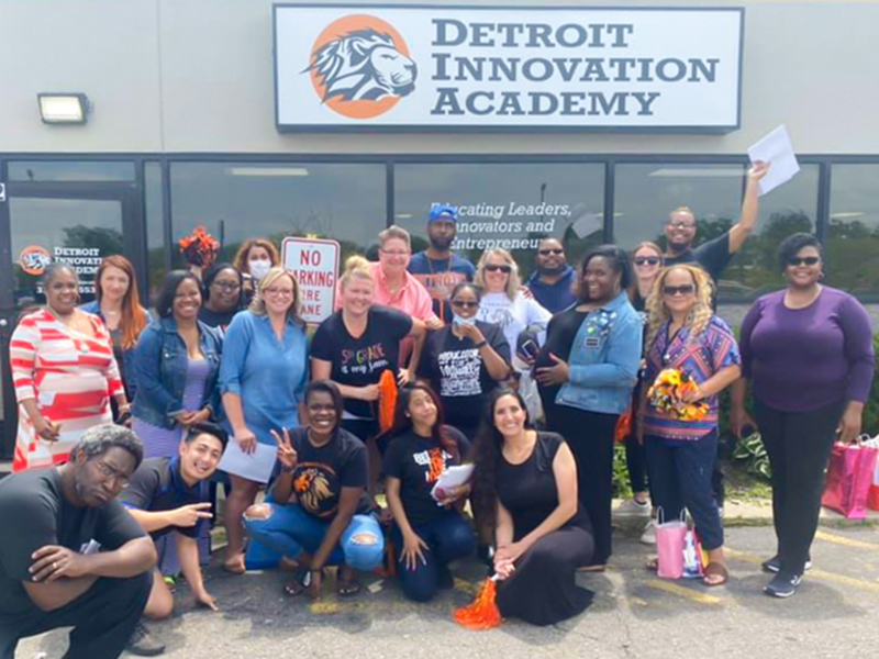 Staff from Detroit Innovation Academy stand in front of entrance smiling for a group photo.