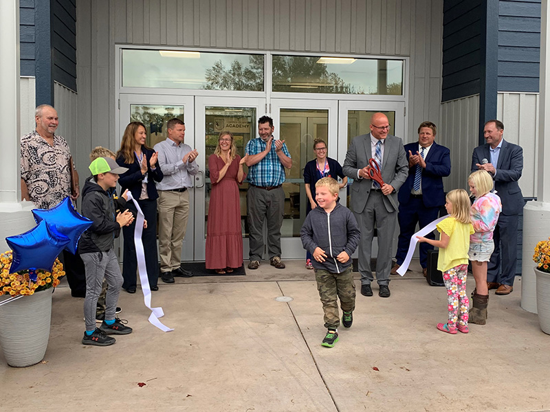 Students, staff, and board members clapping in front of Copper Island Academy after the ribbon was cut at their ribbon cutting ceremony.